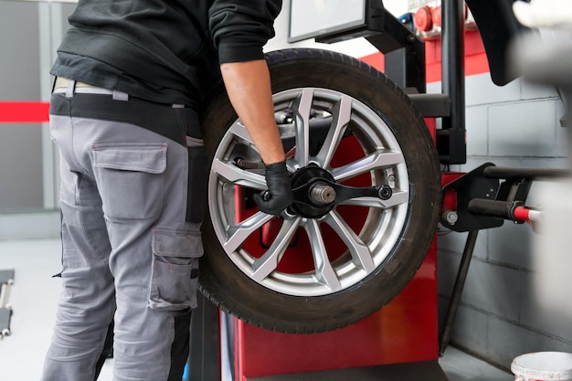 Crop male operator working in tire dealer workshop