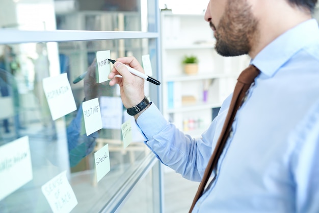 Crop man arranging sticky notes