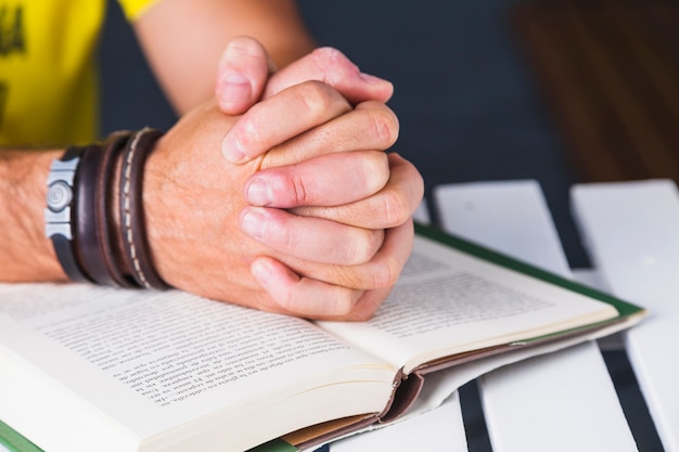 Photo crop man clasping hands over book