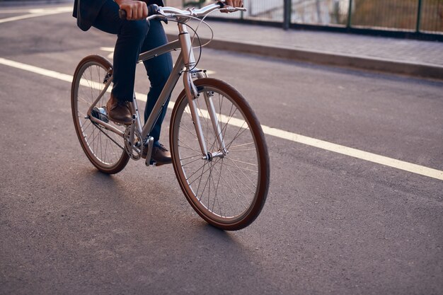 Crop man riding bicycle on road