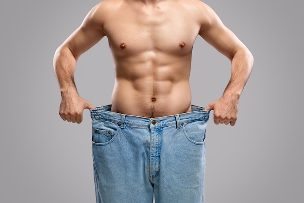 Foto ritaglia l'uomo che mostra i progressi nella perdita di peso