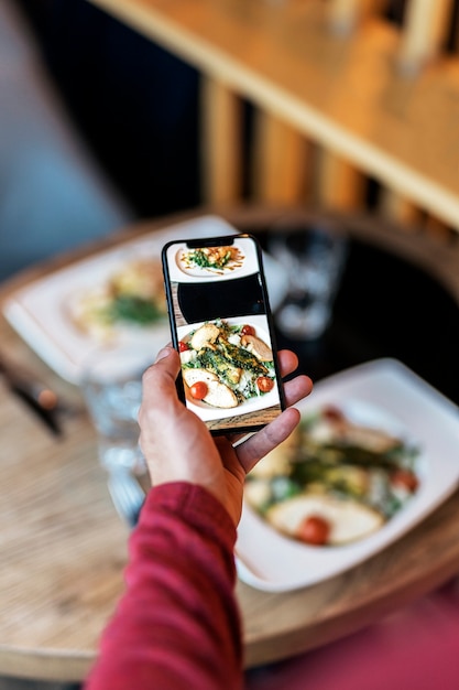 Crop man taking shot of meal on table