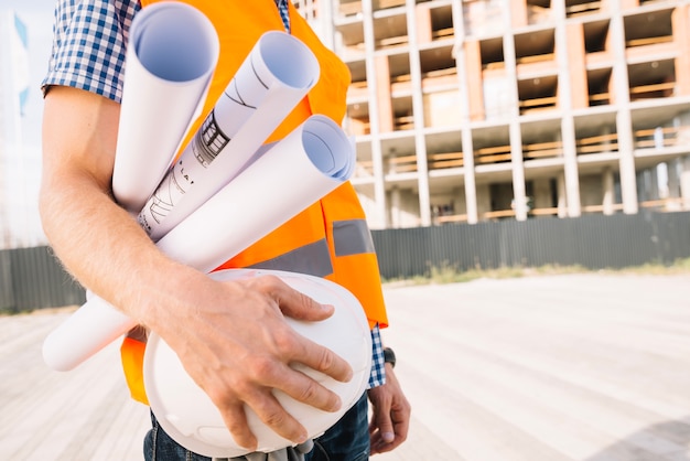 Crop man with drafts and helmet