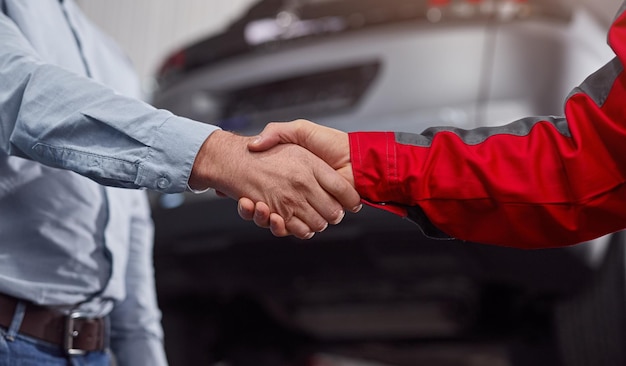 Foto meccanico delle colture e cliente che si stringono la mano