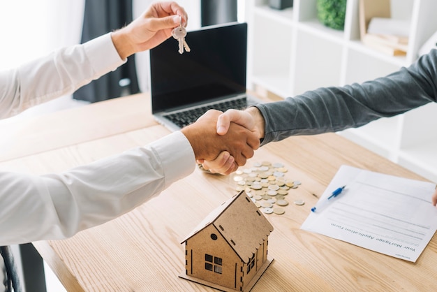 Foto raccolga gli uomini che si stringono la mano nell'agenzia immobiliare