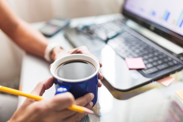 Crop person drinking coffee in office