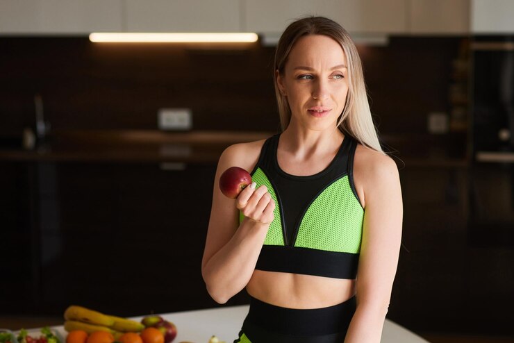 Photo crop photo of young woman in white shirt hold ripe raw fresh apple in hands on kitchen