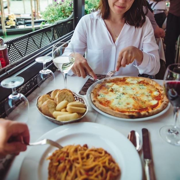 ワインを飲みながらピザを食べるレストランで女性の作物の写真