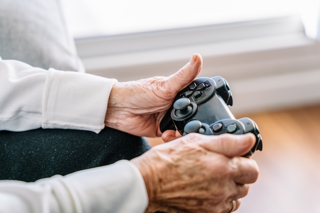 Crop senior woman with gamepad at home