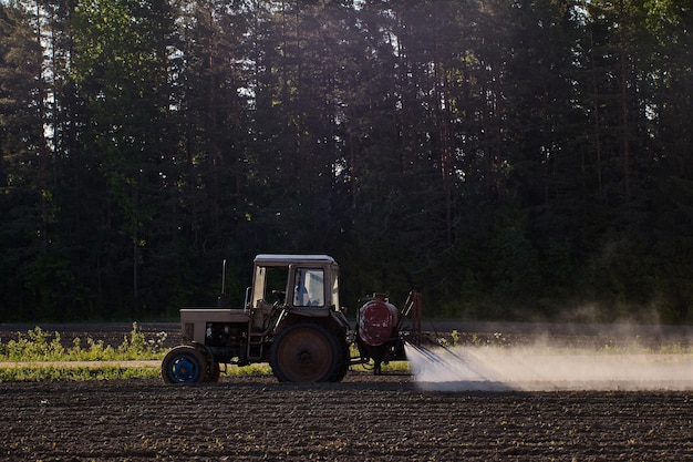 Crop sprayer with farm tractor to apply pesticides in an agricultural field