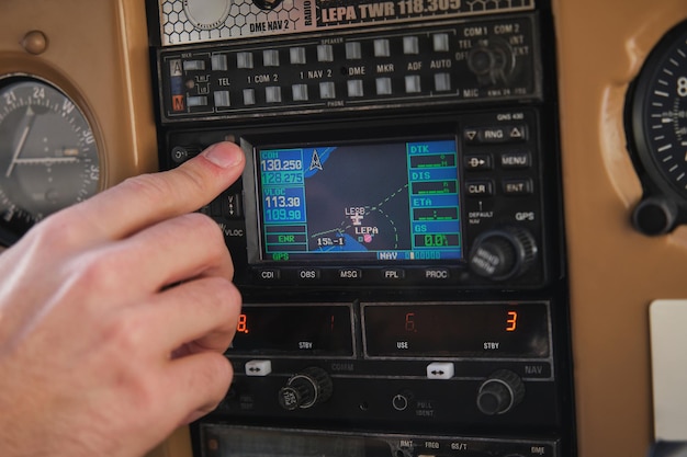 Crop unrecognizable male aviator pushing button on control panel while sitting in cockpit of modern airplane