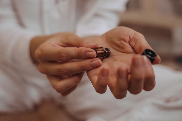 Foto crop vrouw die natuurlijke essentiële olie uit een fles op haar handen aanbrengt tijdens aromatherapie