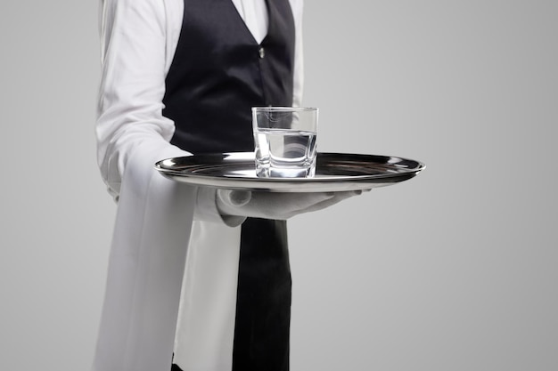 Foto cameriere raccolto con bicchiere d'acqua sul vassoio