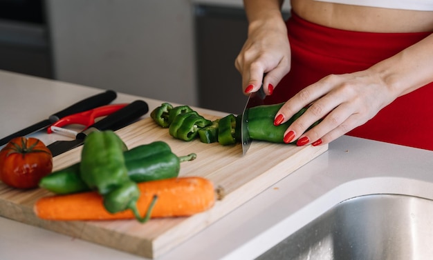 Crop woman cutting pepper for salad