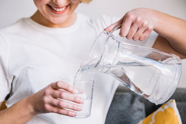 Foto raccolga la donna che riempie di vetro l'acqua