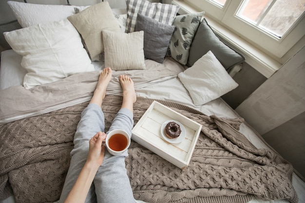 Crop woman having breakfast on bed