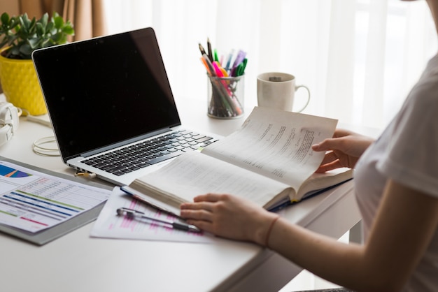 Crop woman reading book in office