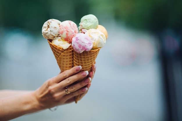 화창한 날 여름 더위에 완벽한 군침이 도는 맛있는 다채로운 아이스크림을 들고 있는 여성의 손에 전문 프랑스 매니큐어가 있는 예쁜 손톱 음식 개념