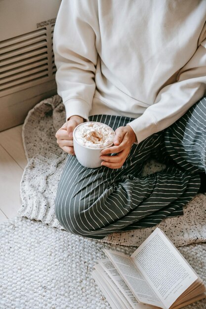 Foto donna del raccolto con una bevanda calda sul pavimento foto