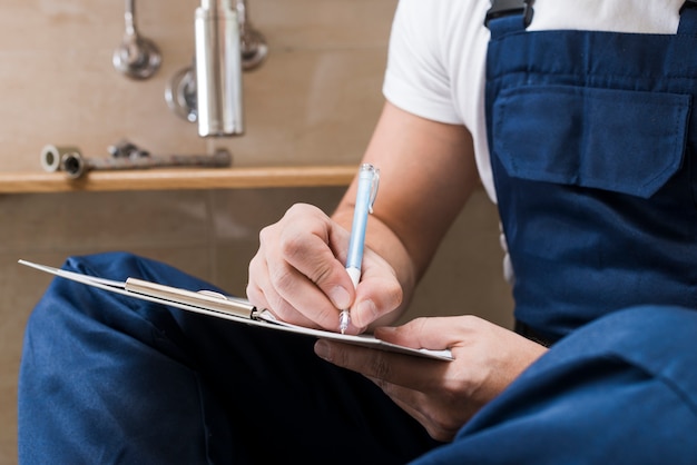 Crop workman writing in paper