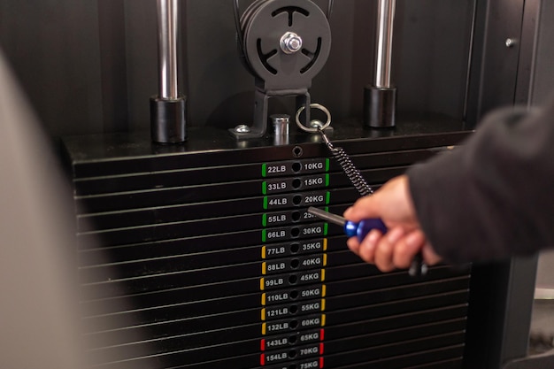 Photo crop young athlete choosing the weight on the gym machine