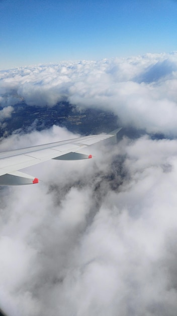 Cropped airplane wing in cloudy sky