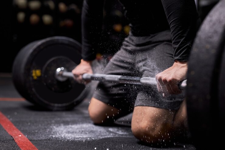Photo 자른 운동 선수 남자는 크로스 핏 훈련을 준비하고 있습니다. cnfident powerlifter는 무거운 무게를 올리기 위해 준비하는 활석을 사용합니다. 현대적인 체육관, 피트니스 센터에서