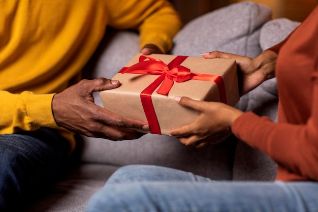 Photo cropped of black couple exchanging gifts at home