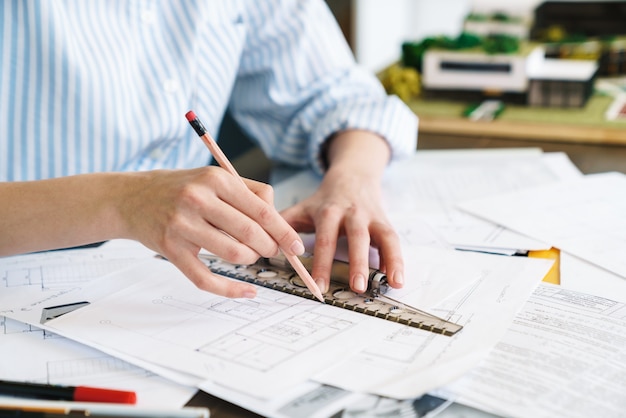 Cropped caucasian woman architect making drawing while designing draft at workplace