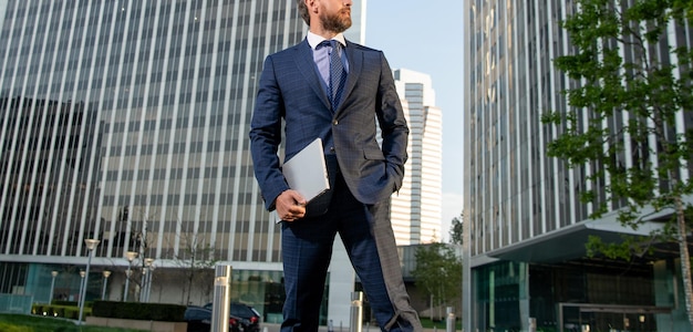 Cropped charismatic mature businessman in suit with laptop\
outside the office freelance