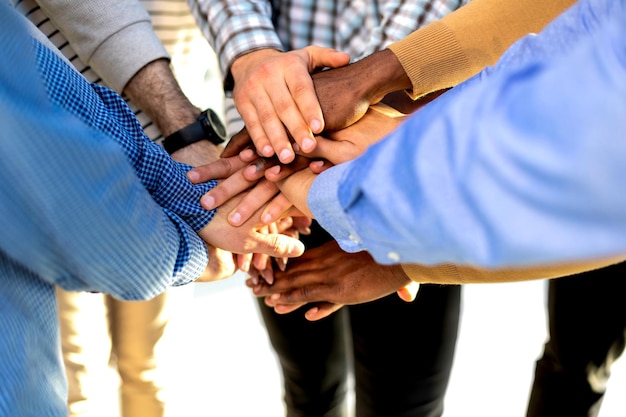 Cropped close of diverse businesspeople putting their hands on top of each other wearing casual clothes and african patterns