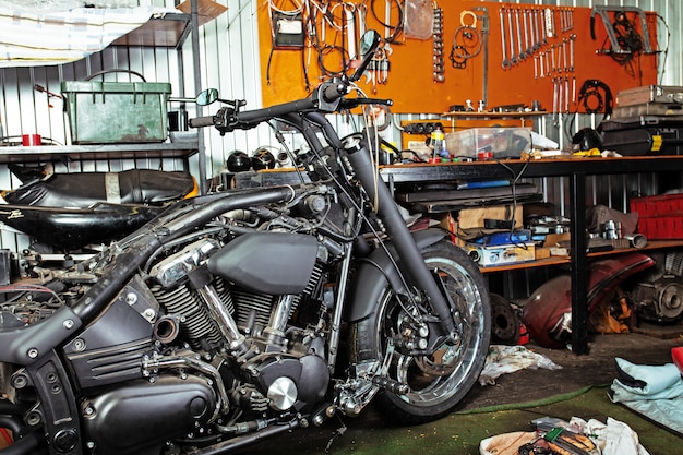 Photo cropped close up shot of beautiful and custom made motorcycle in the workshop