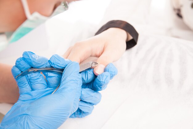 Cropped close up specialist hands making manicure on female hand with special equipment.