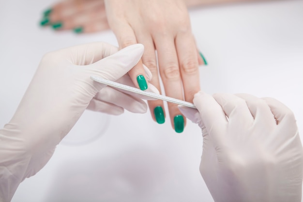 Cropped close up of unrecognizable woman having her nail filed by manicurist