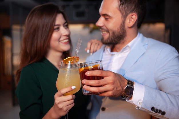 Cropped closeup of a happy loving couple clinking cocktail glasses, celebrating valentines day at  the bar