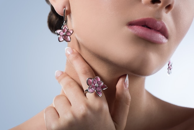 Cropped closeup portrait of a young model posing sensually wearing flower shaped ring and earrings