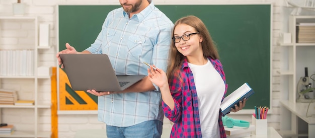 Cropped father and happy child study at school with book and laptop on blackboard background school