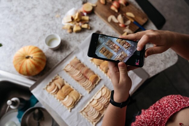 Foto mani femminili tagliate che scattano foto di torta di mele con il cellulare