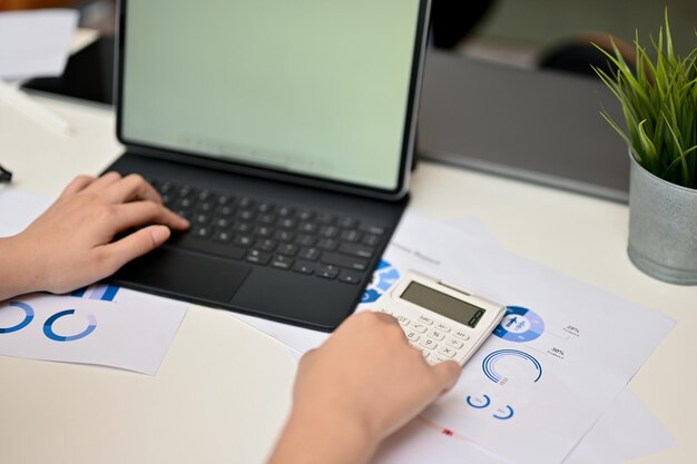 Femmina ritagliata che digita sulla tastiera del tablet portatile e utilizza la calcolatrice