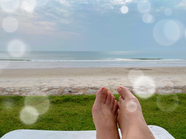 Photo cropped foot of person on beach against sky