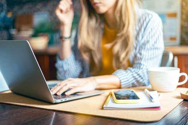 Cropped girl working at laptop indoors.