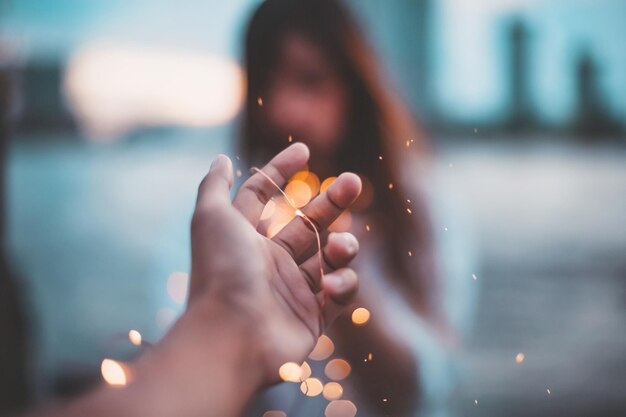 Photo cropped hand against defocused lights and woman