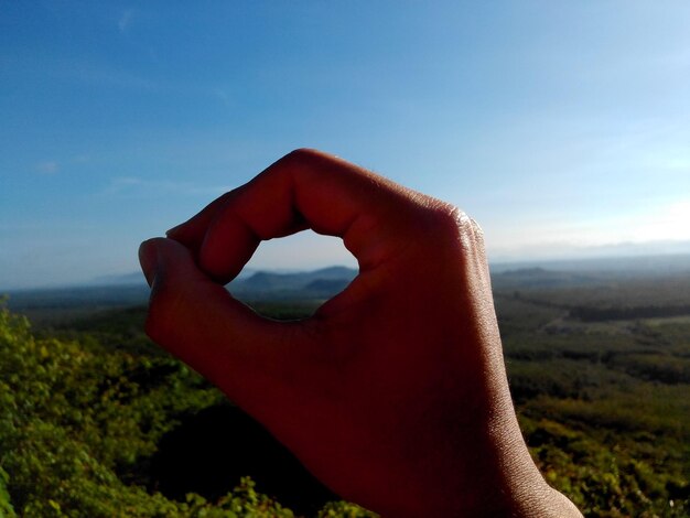 Foto mano tagliata contro il paesaggio