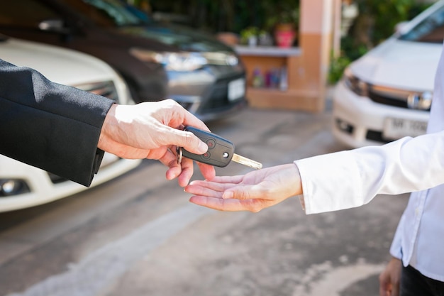 cropped hand of agent giving car key to owner in city