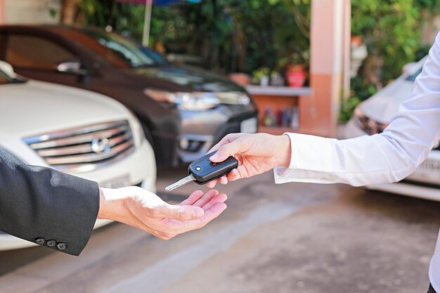 Photo cropped hand of agent giving car key to owner in city