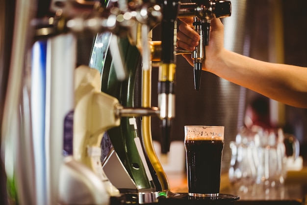 Photo cropped hand of bartender dispensing beer