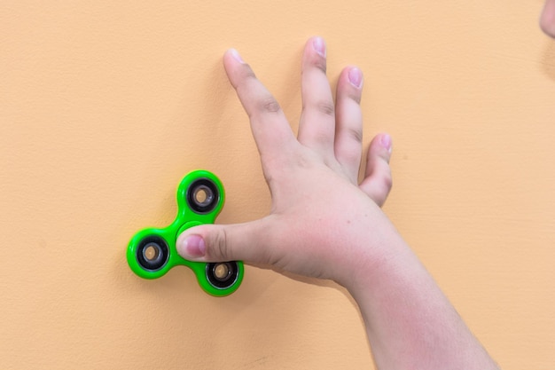 Foto mano tagliata di un ragazzo che gioca con un spinner fidget sul muro
