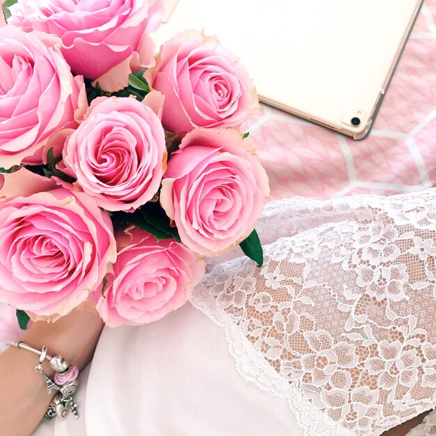 Foto la mano tagliata della sposa che tiene un bouquet di rose sul letto