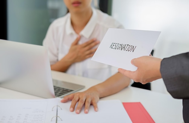 Photo cropped hand of business person giving resignation letter to colleague in office