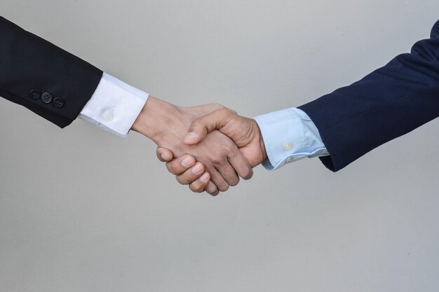 Cropped hand of business person shaking hand against gray background